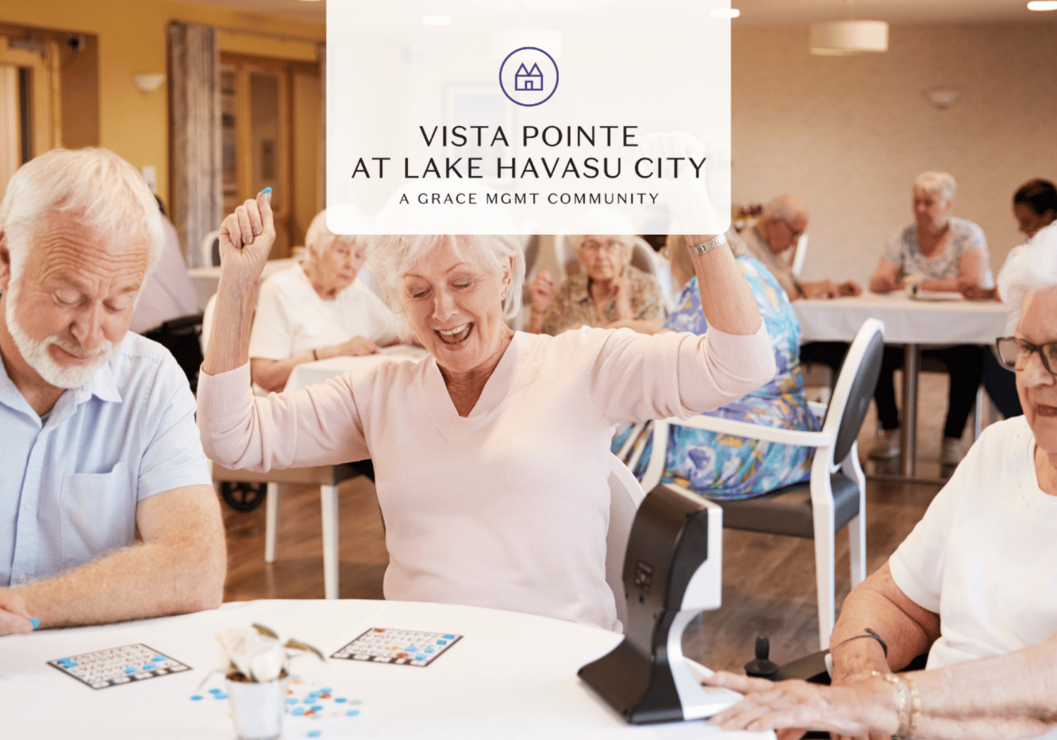 Senior woman cheerfully raises her arms while playing a game with others at a retirement community gathering.